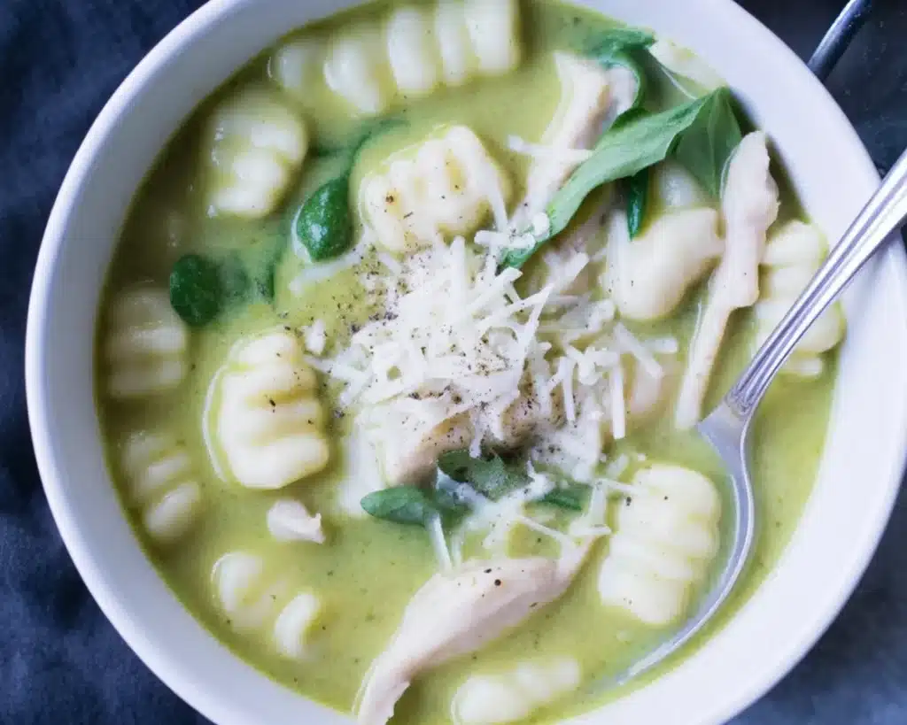 Creamy Pesto Chicken Gnocchi Soup served in a bowl with fresh spinach and herbs.