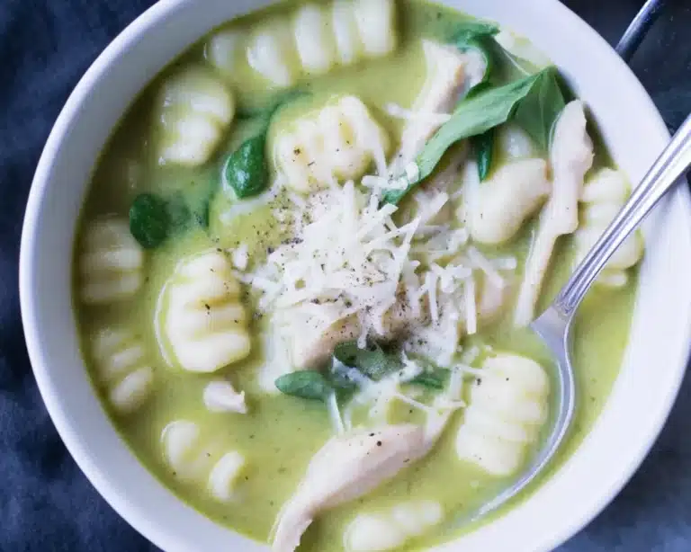 Creamy Pesto Chicken Gnocchi Soup served in a bowl with fresh spinach and herbs.