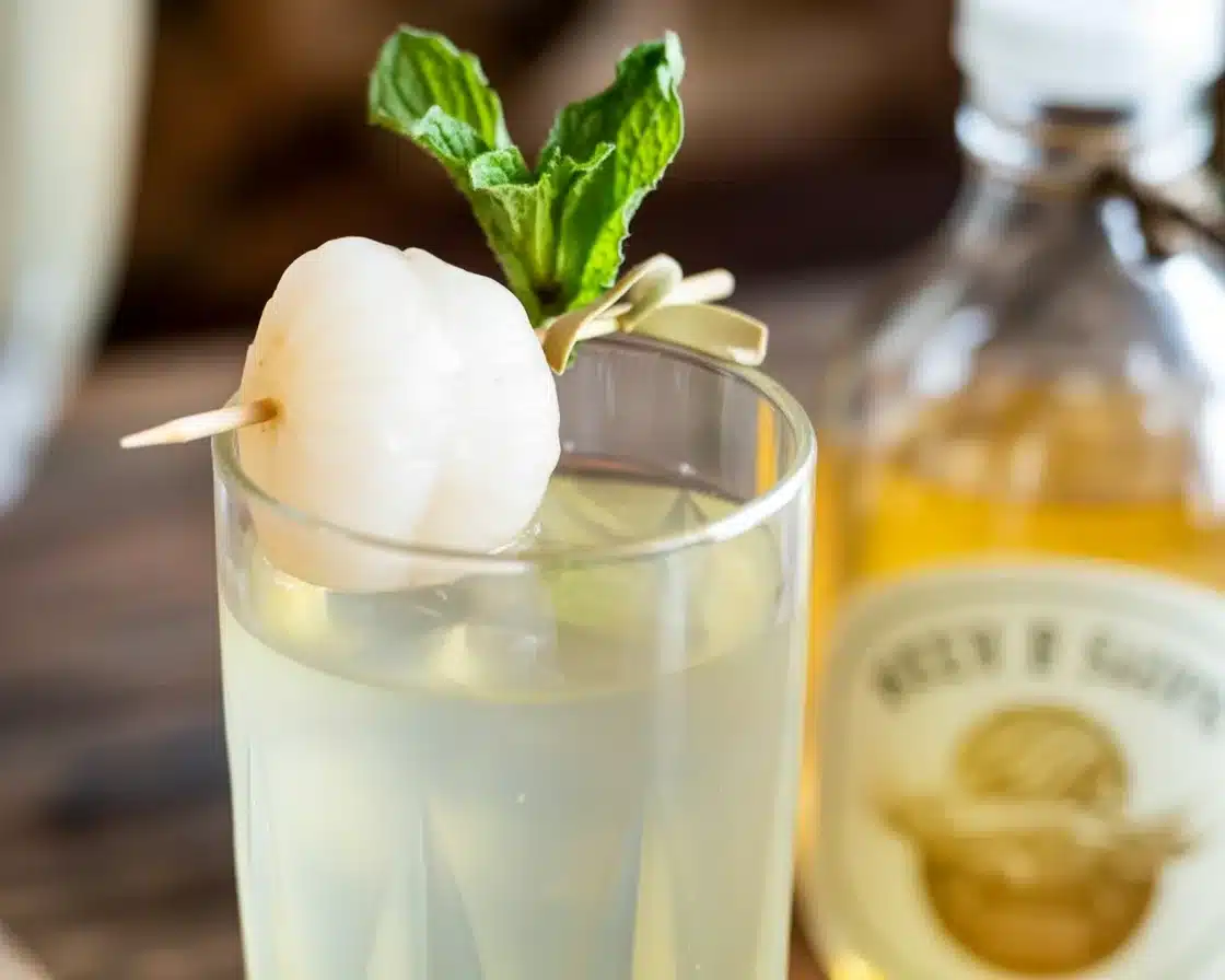 Lychee Ginger Spritz cocktail garnished with fresh mint leaves and served in a glass.